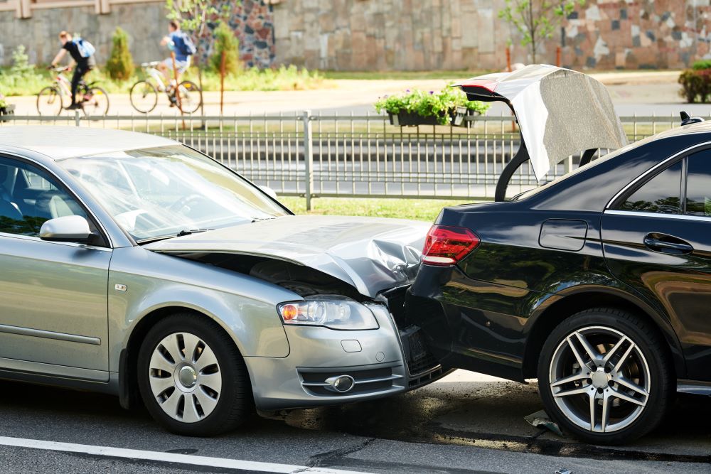 Silver car hitting back of black car in car accident