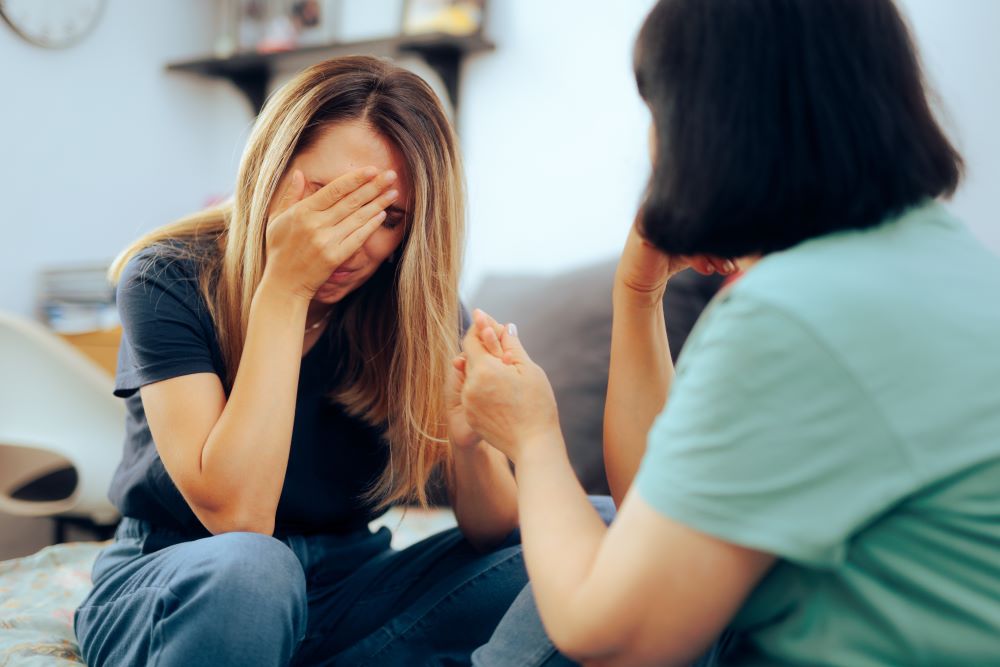 woman upset while another woman comforts her